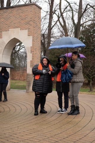 Caryn Cruz (center) and other coordinators of “Take Back the Night” gathered at the Andrews globe for the start of the April 2 march.